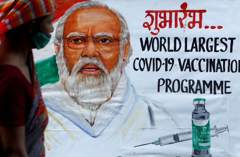 A woman walks past a painting of Indian Prime Minister Narendra Modi a day before the inauguration of the COVID-19 vaccination drive on a street in Mumbai, India, January 15, 2021. (photo credit: REUTERS/FRANCIS MASCARENHAS)