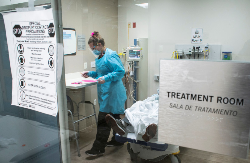 A healthcare worker treats a coronavirus disease (COVID-19) positive patient inside a COVID-19 unit at Trinitas Regional Medical Center in Elizabeth (photo credit: EDUARDO MUNOZ / REUTERS)