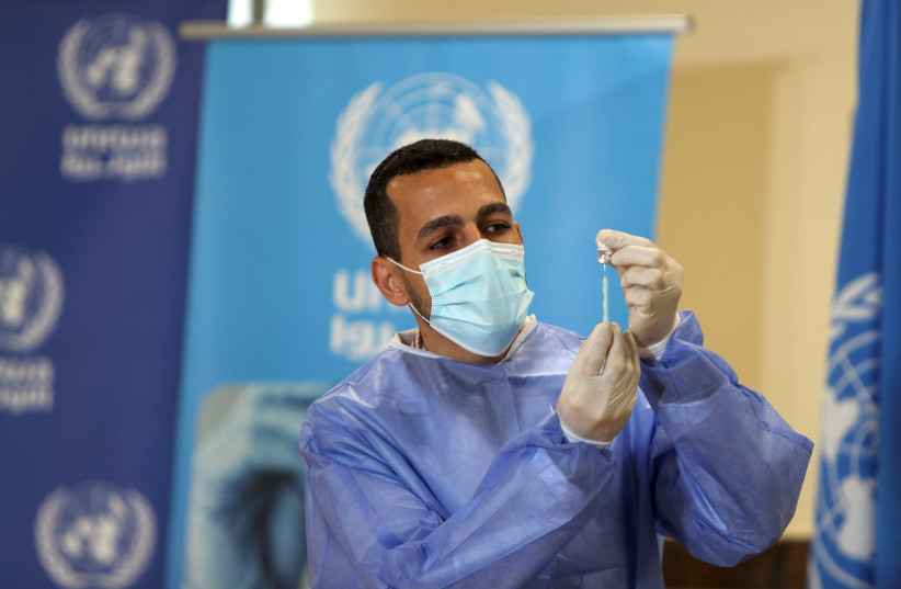 A Palestinian health worker prepares to vaccinate Matthias Schmale, UNRWA's Gaza director, against the coronavirus disease (COVID-19), in Gaza City February 24, 2021.  (photo credit: REUTERS)