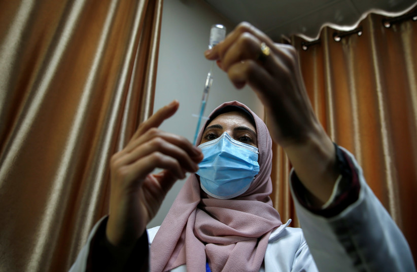 A Palestinian health worker prepares a coronavirus disease (COVID-19) vaccine in Gaza City February 22, 2021.  (photo credit: REUTERS)