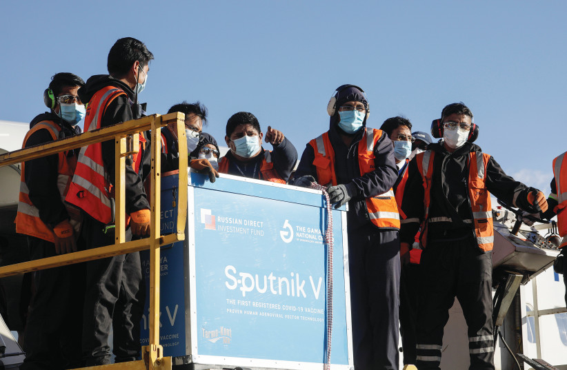 WORKERS UNLOAD containers transporting the first batch of Russia’s Sputnik V COVID-19 vaccine at an airport on the outskirts of La Paz, Bolivia, in January. (photo credit: DAVID MERCADO/REUTERS)