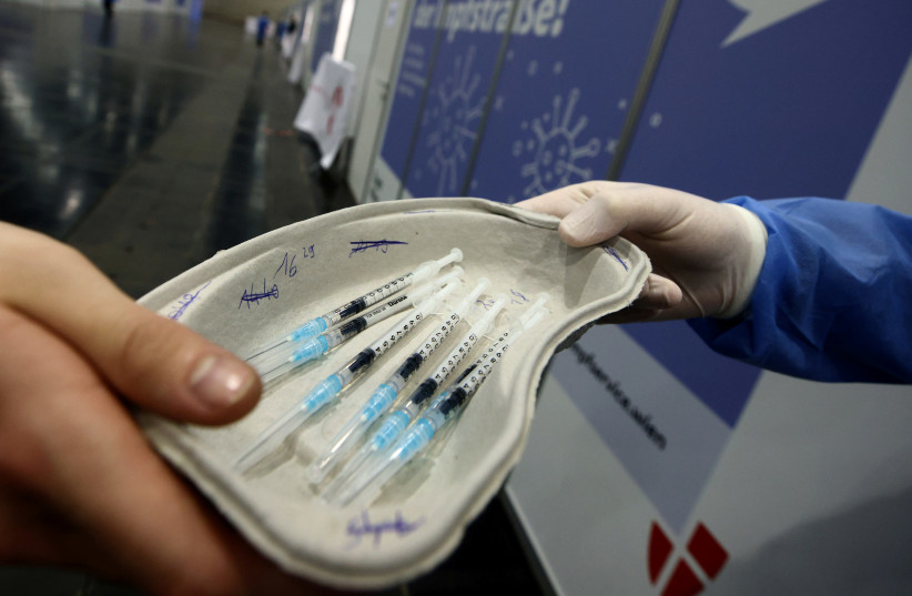 A healthcare worker hands over doses of the Pfizer-BioNTech COVID-19 vaccine to a doctor at Messe Wien Congress Center, which has been set up as coronavirus disease vaccination centre, in Vienna, Austria February 7, 2021. (credit: REUTERS/LISI NIESNER/FILE PHOTO)