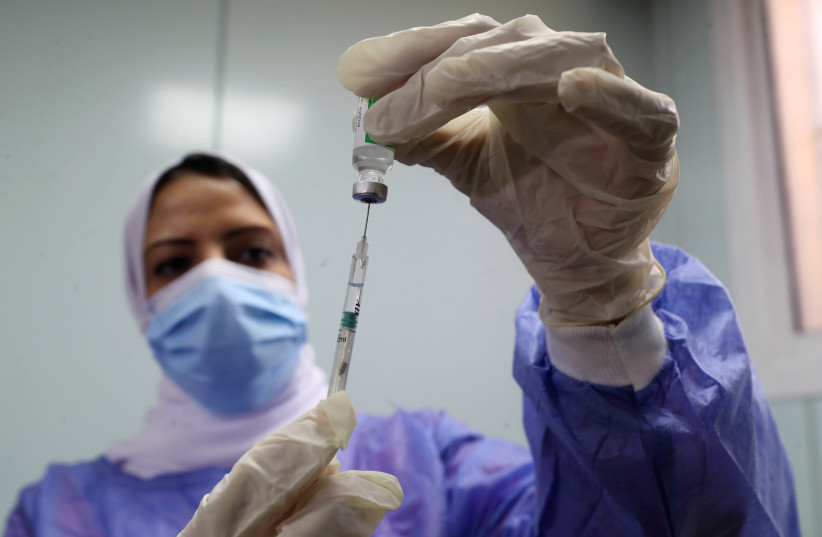 A healthcare worker holds a syringe and vaccine vial against the coronavirus disease (COVID-19) in Cairo, Egypt March 4, 2021. (photo credit: REUTERS/MOHAMED ABD EL GHANY)