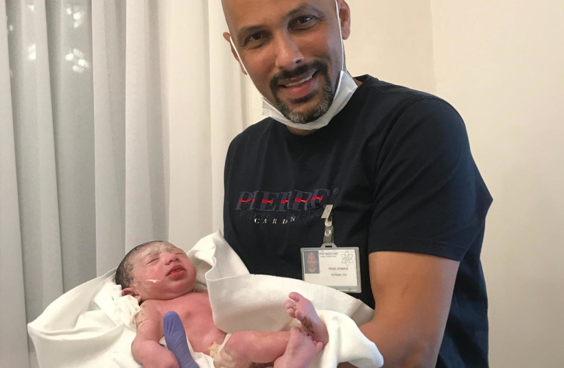 Ambulance driver Khaled Schachde with the newborn baby girl he helped deliver, March 18, 2021. (photo credit: GALILEE MEDICAL CENTER)