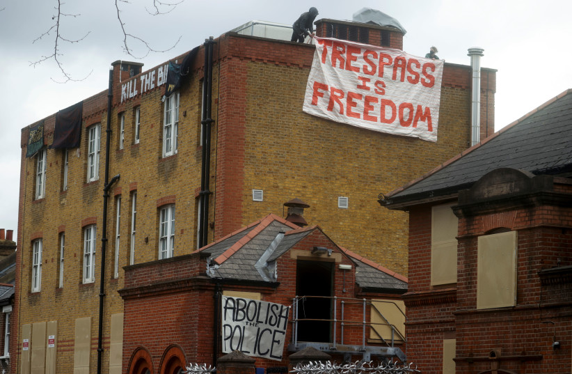 Protesters hang a banner at a former police station in Clapham, near to where Sarah Everard was kidnapped, as part of continued demonstrations against the police, in London, Britain March 25, 2021. (photo credit: HANNAH MCKAY/ REUTERS)
