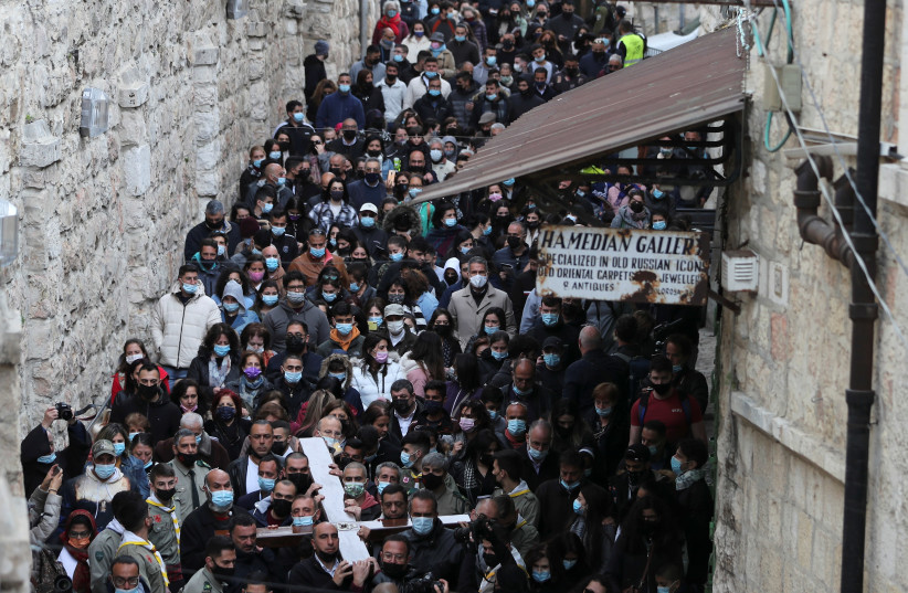 Christian worshippers take part in a Good Friday procession along the Via Dolorosa amid eased coronavirus disease (COVID-19) restrictions, during Easter Holy Week in Jerusalem's Old City April 2, 2021.  (credit: AMMAR AWAD/REUTERS)