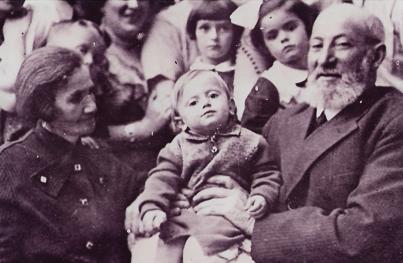 The writer’s grandfather, Avraham, with one of the children, probably Nutek, on his knee (photo credit: Courtesy)