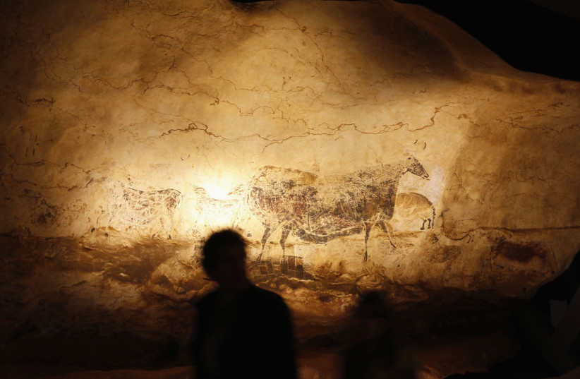 A man looks at a reproduction of the Lascaux caves paintings at the Cap Science's exhibition hall in Bordeaux, October 12, 2012. (photo credit: REGIS DUVIGNAU/REUTERS)