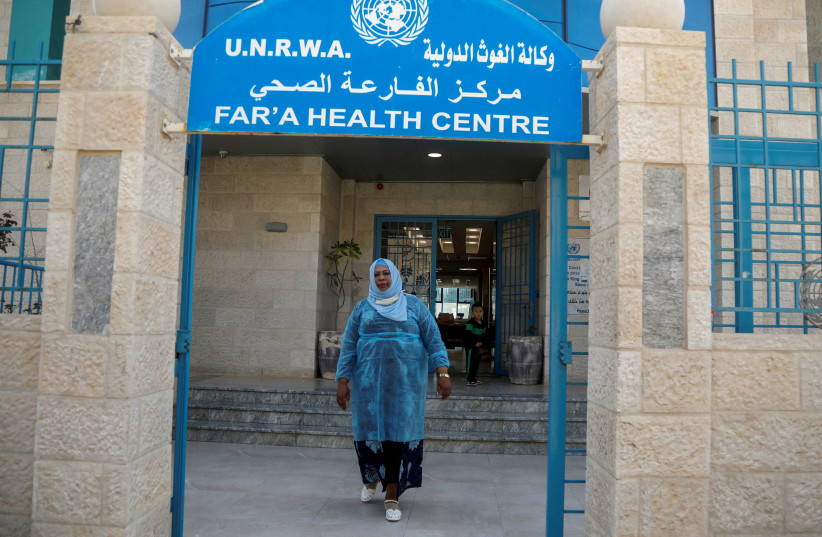 A Palestinian health worker leaves a health center run by the United Nations Relief and Works Agency (UNRWA), at al-Fari'ah refugee camp, in the Israeli-occupied West Bank April 8, 2021. (photo credit: RANEEN SAWAFTA/ REUTERS)