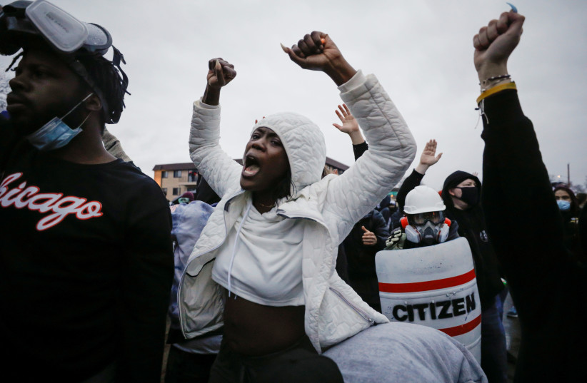 Protesters gesture as they gather at the gate of the Brooklyn Center Police Department a day after Daunte Wright was shot and killed by a police officer, in Brooklyn Center, Minnesota, US, April 12, 2021.  (photo credit: REUTERS/NICK PFOSI)
