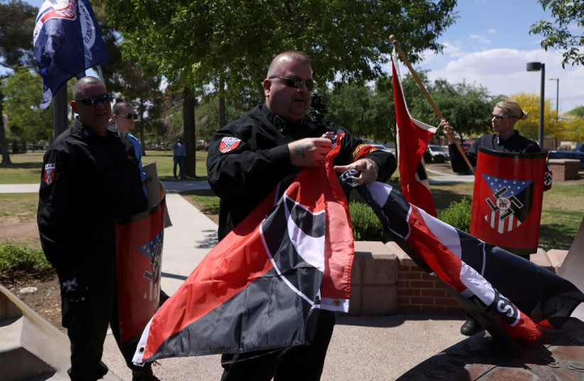 Burt Colucci of the white nationalist group National Socialist Movement destroys a flag of the anti-facist movement during a rally in Phoenix, Arizona, U.S., April 17, 2021. (credit: JIM URQUHART/REUTERS)