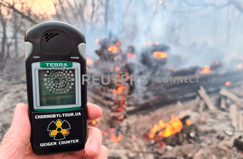 A geiger counter measures a radiation level at a site of fire burning in the exclusion zone around the Chernobyl nuclear power plant, outside the village of Rahivka, Ukraine April 5, 2020. (credit: YAROSLAV YEMELIANENKO/REUTERS)