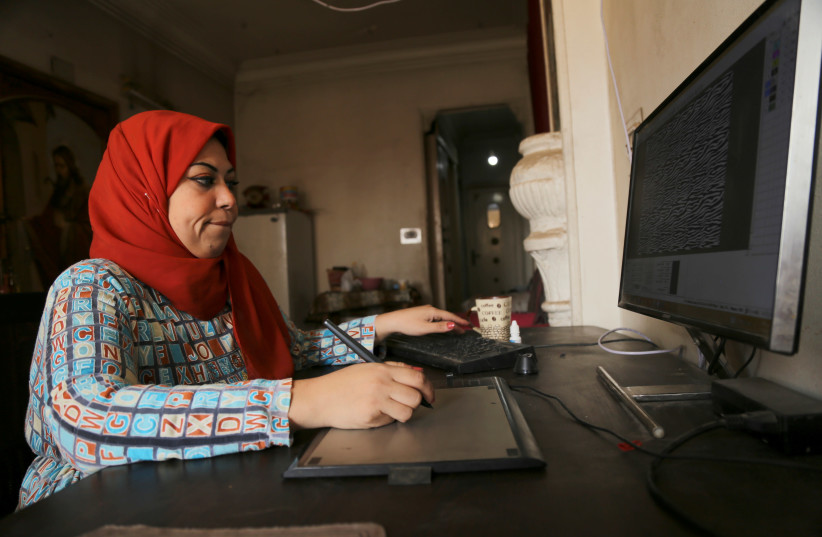 Nesma Nasr, an Egyptian textile engineer, works on her computer at her home in Cairo, Egypt March 26, 2021. Picture taken March 26, 2021.  (credit: REUTERS/HANAA HABIB)