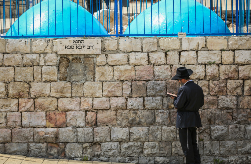 Ultra-Orthodox Jewish man prays outside the Tomb of Rabbi Shimon bar Yochai on Mt. Meron in northern Israel on May 6, 2020 (photo credit: DAVID COHEN/FLASH 90)