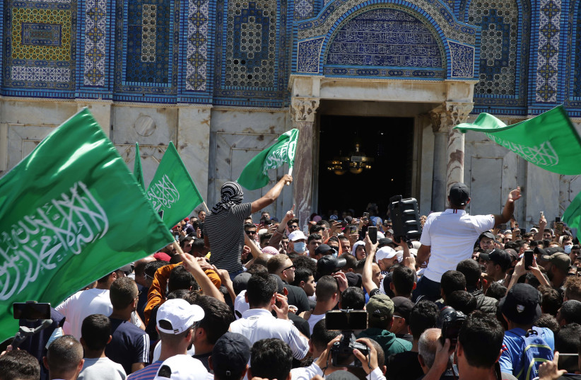 People hold Hamas flags as Palestinians gather after performing the last Friday of Ramadan to protest over the possible eviction of several Palestinian families from homes on land claimed by Jewish settlers in the East Jerusalem neighborhood of Sheikh Jarrah, May 7, 2021.  (credit: JAMAL AWAD/FLASH90)
