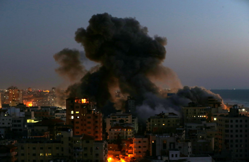 Smoke rises from a building after it was destroyed by Israeli air strikes amid a flare-up of Israeli-Palestinian violence, in Gaza May 11, 2021 (photo credit: REUTERS/IBRAHEEM ABU MUSTAFA)