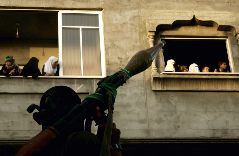 Hamas supporters watch armed Hamas militants parade in central Gaza City. (photo credit: REUTERS)