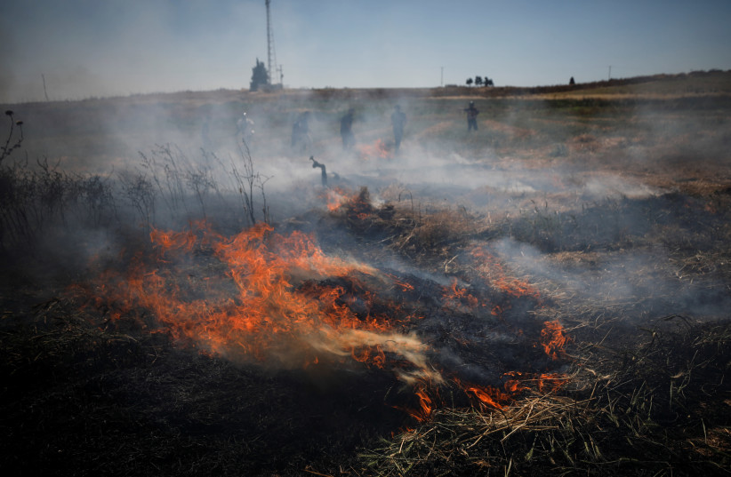 A fire burns on a field of wheat after a rocket launched from the Gaza Strip landed near homes in Moshav Zohar, Israel May 13, 2021. (credit: AMIR COHEN/REUTERS)