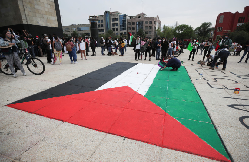 People stand near a Palestinian flag painted on the ground at the Monument to the Revolution during a pro-Palestine demonstration, amid the escalating flare-up of Israeli-Palestinian violence, in Mexico City, Mexico May 15, 2021. (credit: HENRY ROMERO / REUTERS)
