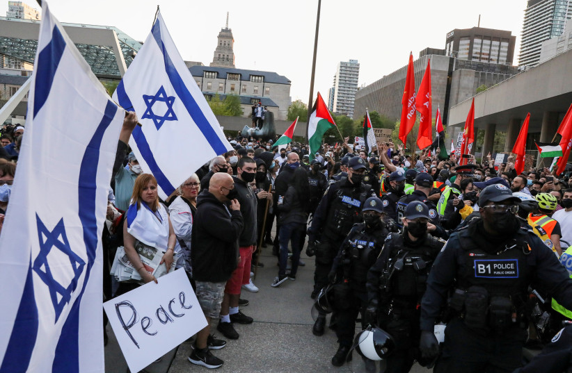 Police officers stand in line to separate protesters supporting the Palestinians from a small group of Israel supporters in front of city hall in Toronto, Ontario, Canada May 15, 2021. (credit: REUTERS/CHRIS HELGREN)