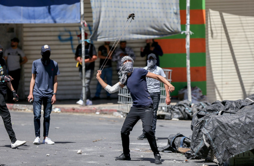 Palestinian youth clash with Israeli security forces in Hebron, May 18, 2021 (credit: WISAM HASHLAMOUN/FLASH90)
