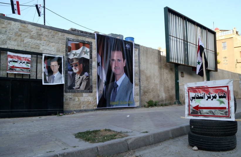 Posters of Syria's President Bashar Assad are seen outside a polling station before polls open for the presidential elections, in Damascus, Syria May 26, 2021.  (credit: YAMAM AL SHAAR/REUTERS)