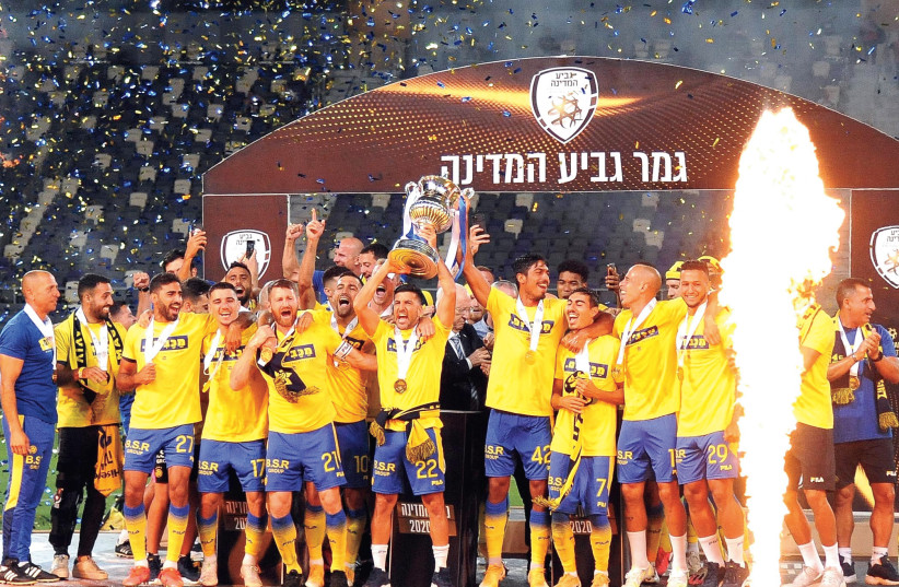 MACCABI TEL AVIV celebrates on the pitch with the trophy after beating Hapoel Tel Aviv 2-1 in extra time on Wednesday at Bloomfield to win the Israel State Cup. (credit: BERNEY ARDOV)