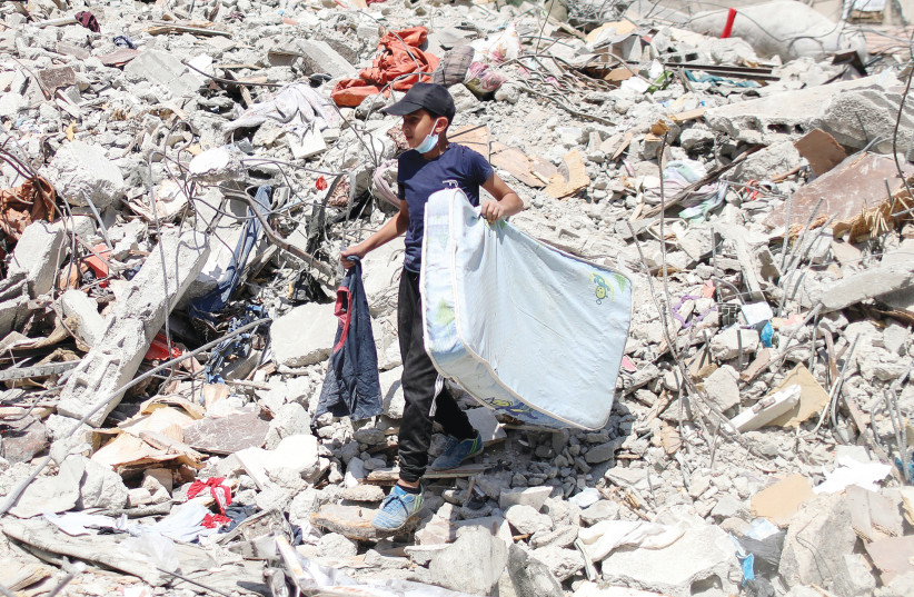 A BOY CARRIES a mattress amid the debris of a house destroyed during Israeli-Palestinian fighting, in Gaza City on Wednesday. (photo credit: MOHAMMED SALEM/REUTERS)