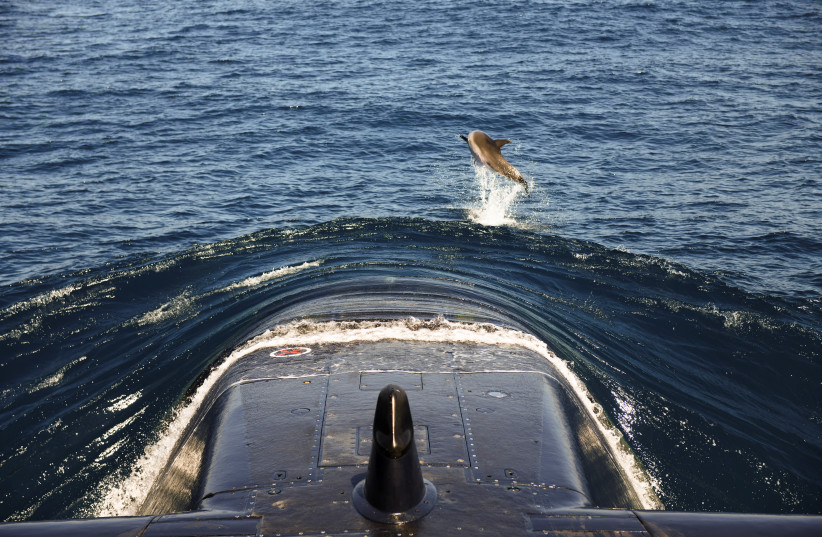A dolphin leaps near the bow of Israeli navy submarine Leviathan during a sailing accompanied by a Reuters correspondent, in the Mediterranean Sea off the coast of Haifa. (photo credit: IDF SPOKESPERSON UNIT VIA REUTERS)