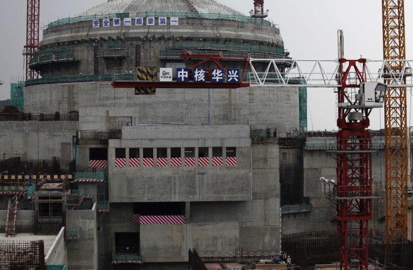 Workers (bottom) stand in front of a nuclear reactor as part of the Taishan Nuclear Power Plant seen under construction in Taishan, Guangdong province, October 17, 2013. (photo credit: BOBBY YIP/ REUTERS)