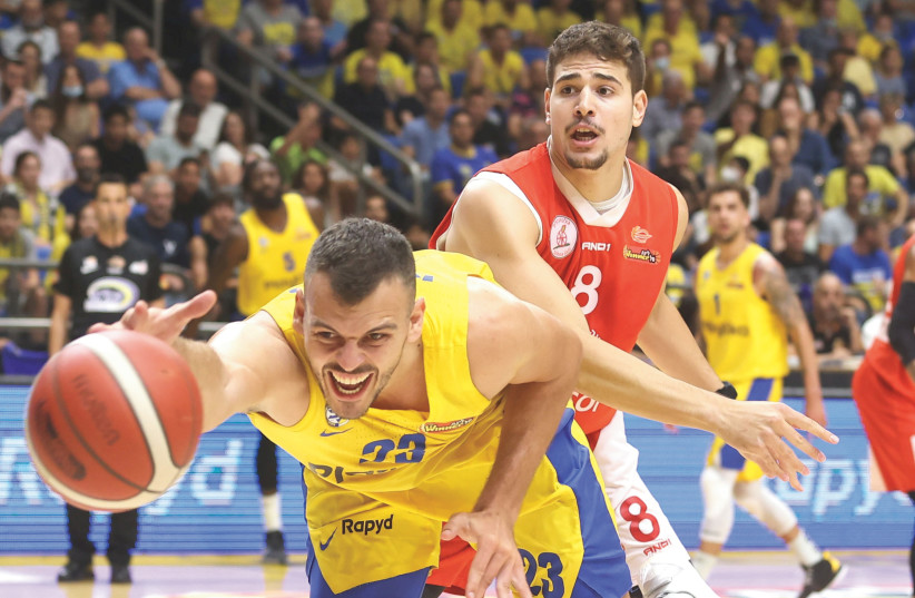 MACCABI TEL AVIV center Ante Zizic dives for a loose ball in front of Hapoel Gilboa/Galil forward Yotam Hanochi during the yellow-and-blue’s 83-74 victory on Monday night at Yad Eliyahu in Game 1 of the best-of-three Winner League finals. (credit: DANNY MARON)
