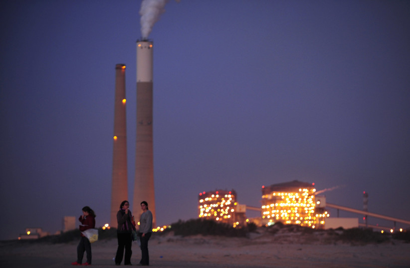 Israelis stand on beach in front of a coal power station in Ashkelon (photo credit: AMIR COHEN/REUTERS)