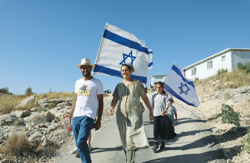 ISRAELIS WALK with flags in the Bat Ayin settlement in Gush Etzion on the West Bank, last month.  (credit: GERSHON ELINSON/FLASH90)