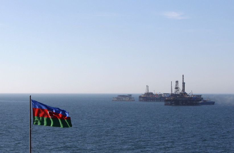 An Azerbaijan state flag flutters in the wind on an oil platform in the Caspian Sea (credit: DAVID MDZINARISHVILI/REUTERS)