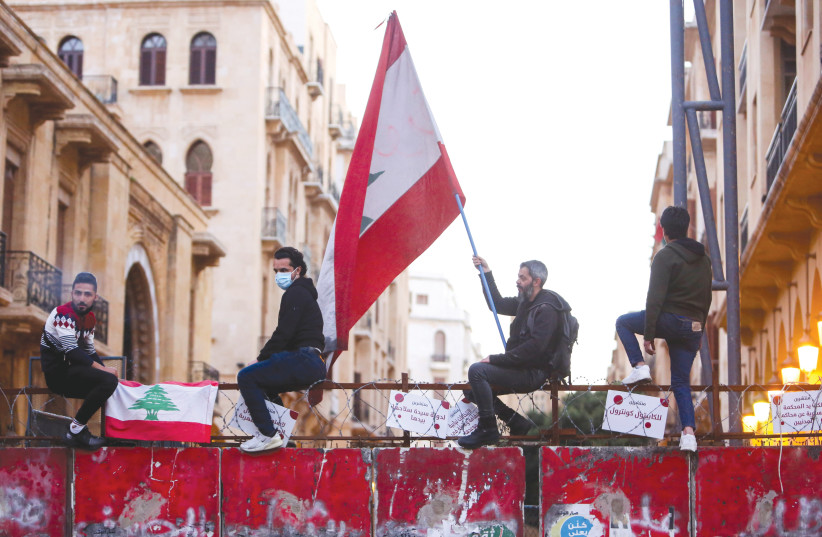 A DEMONSTRATOR holds a Lebanese flag during a protest against the fall in the Lebanese pound and mounting economic hardships, in Beirut in March. (photo credit: AZIZ TAHER/REUTERS)