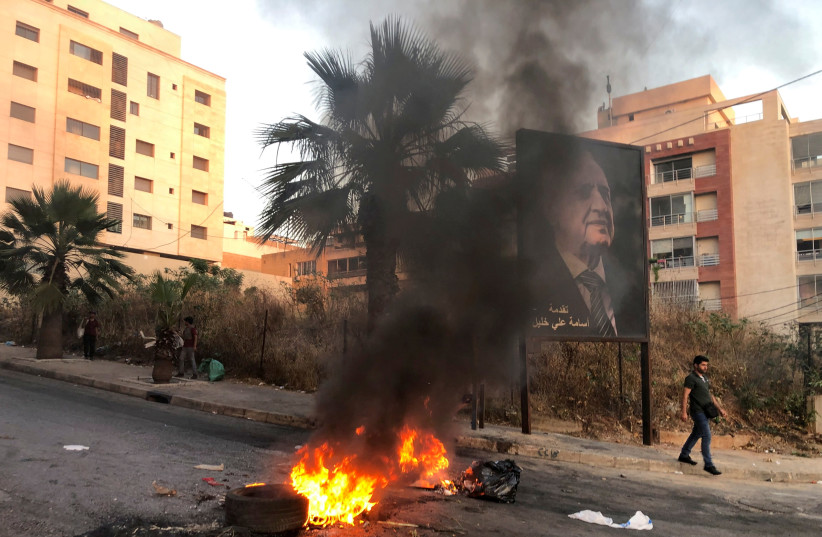 A man walks near a burning fire blocking a road, during a protest against mounting economic hardships, in Beirut, Lebanon June 28, 2021. (credit: REUTERS/ISSAM ABDALLAH)