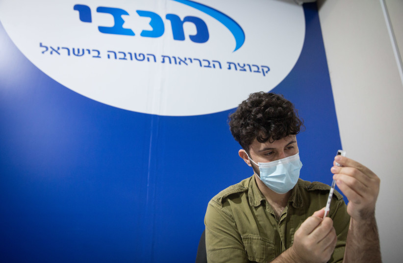 Israelis receive a COVID-19 vaccine, at a Maccabi Health vaccination center at the Givatayim mall, outside of Tel Aviv, January 20, 2021. (credit: MIRIAM ALSTER/FLASH90)
