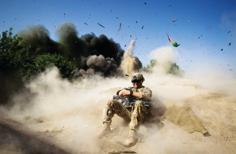 A US SOLDIER takes cover during a controlled detonation in southern Afghanistan’s Kandahar Province in 2012. (credit: SHAMIL ZHUMATOV / REUTERS)