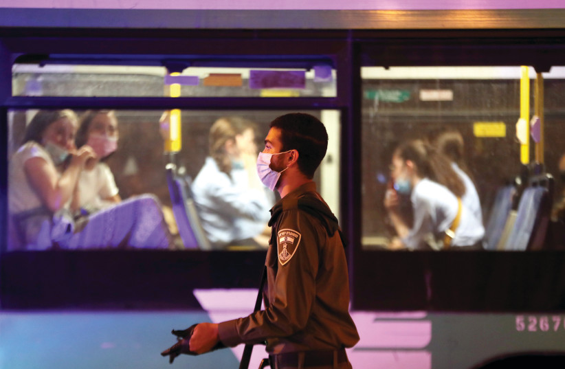 Two women look out of a bus as an Israel Police officer walks past. (credit: REUTERS)