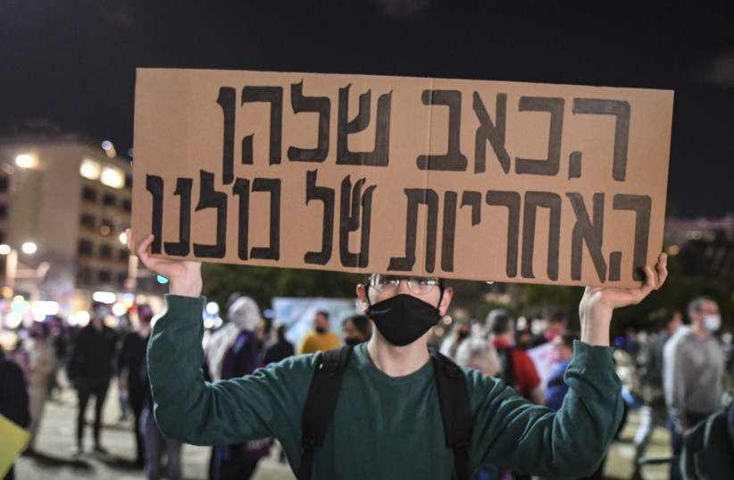 A demonstrator holds a sign reading "their pain is the responsibility of all of us," as Jewish and Arab Israelis protest in Tel Aviv against police inaction, the surging crime and violence in Arab communities  on March 13, 2021. (photo credit: FLASH90)