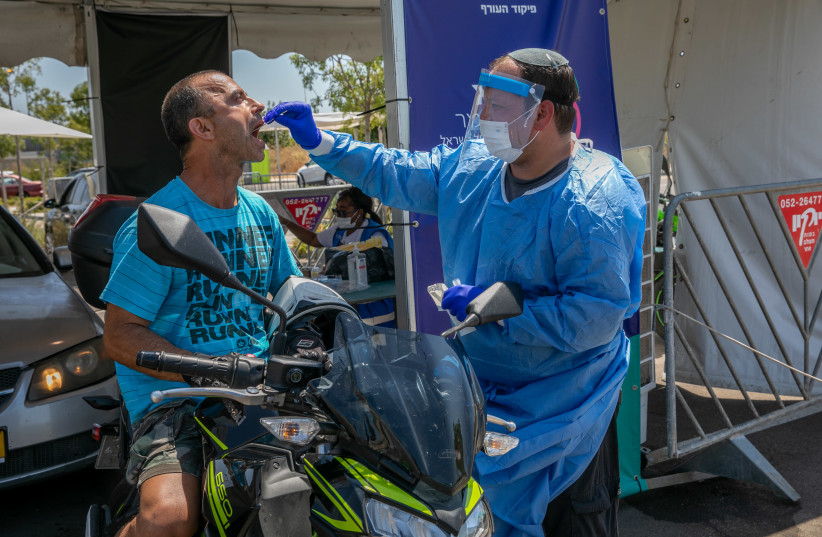 Health care workers take test samples of Israelis in a drive through complex to check if they have been infected with the Coronavirus, in Modi'in, on July 21, 2021.  (credit: YOSSI ALONI/FLASH90)