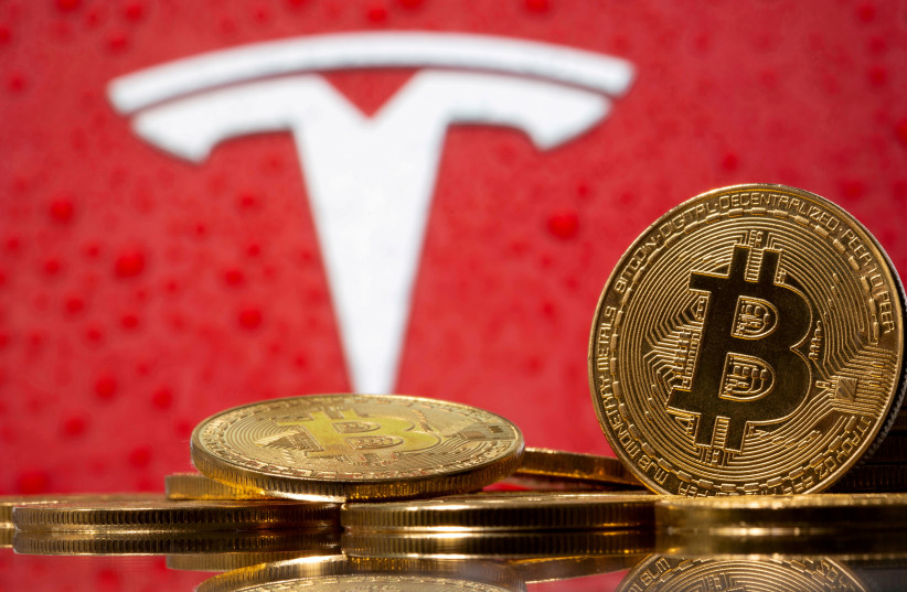  Representations of virtual currency bitcoin are seen in front of Tesla logo in this illustration (photo credit: REUTERS/DADO RUVIC/FILE PHOTO)