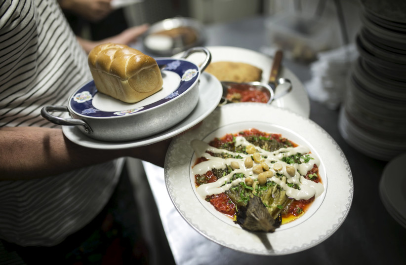 A waiter carries plates of vegan food at Georgian restaurant Nanuchka in Tel Aviv. Nana Shrier, the owner of Nanuchka, shocked Israel’s culinary world when she removed all animal-based products from the menu in 2015. (photographer: BAZ RATNER/REUTERS)