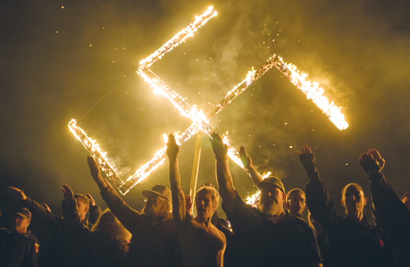 WHITE NATIONALISTS give Nazi salutes during a swastika burning in the US State of Georgia in 2018. (photo credit: GO NAKAMURA/REUTERS)