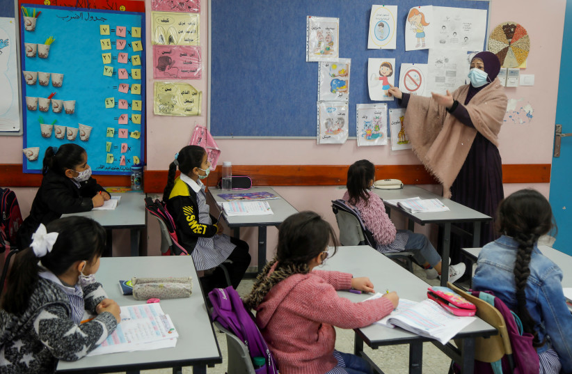 A Palestinian teacher conducts a class for students in an UNRWA-run school that reopened after the coronavirus disease (COVID-19) restrictions were eased, at al-Fari'ah refugee camp, in the West Bank April 12, 2021.  (credit: RANEEN SAWAFTA/ REUTERS)