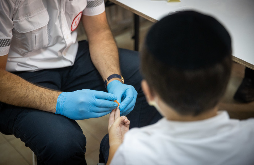  A Magen David Adom (MDA) worker taking a serological tests for COVID-19 from an ultra-Orthodox child in the ultra-Orthodox town of Kiryat Ye’arim (Telz-Stone), outside Jerusalem, August 9, 2021. (credit: YONATAN SINDEL/FLASH90)