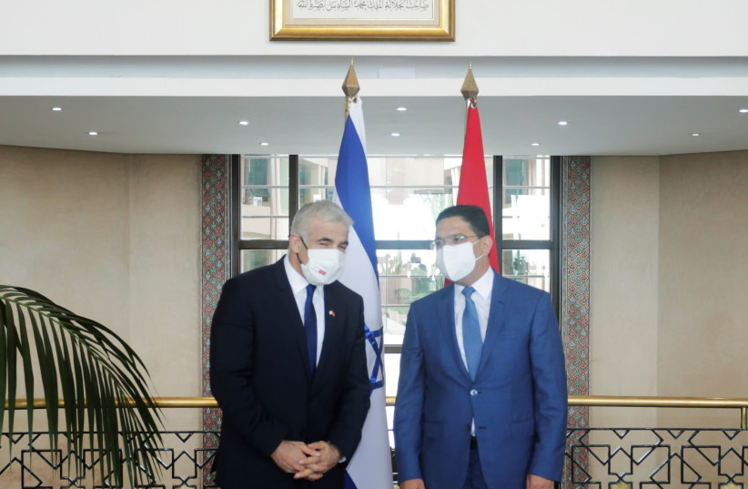 Israeli Foreign Minister Yair Lapid walks stands next to his Moroccan counterpart Nasser Bourita as they meet in Rabat, Morocco August 11, 2021 (credit: REUTERS/YOUSSEF BOUDLAL)