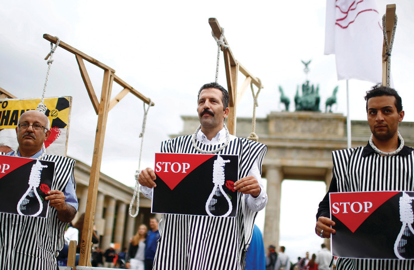 PROTESTERS DEMONSTRATE in front of Berlin’s Brandenburg Gate in August 2016 against the execution by Iran of up to 20 Kurds suspected of attacking security forces.  (photo credit: HANNIBAL HANSCHKE/REUTERS)