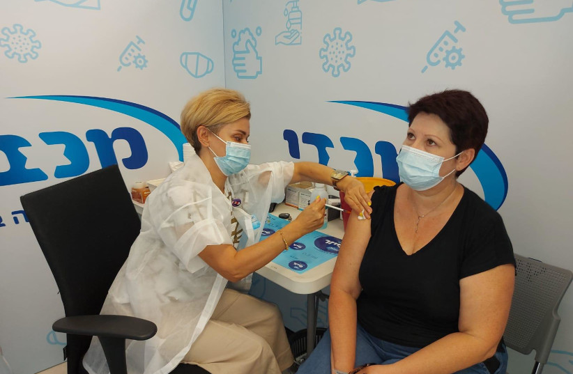 Laura Ludmila Weissman is seen getting a COVID-19 vaccine at Maccabi in Rishon Lezion from nurse Olga Gregoriev. (photo credit: MACCABI HEALTHCARE SERVICES SPOKESPERSON)