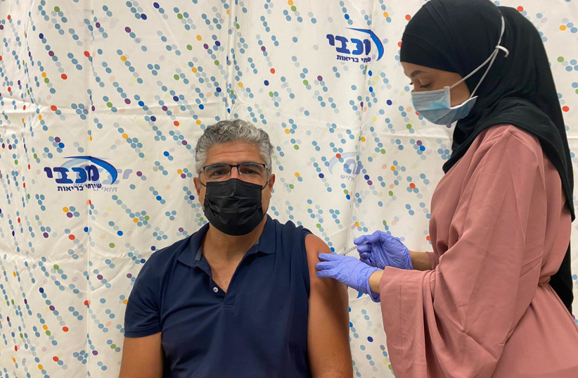 A man is seen getting vaccinated against COVID-19 at the Maccabi clinic in Jaffa from nurse Doa Sheikh-Yehia.  (credit: MACCABI HEALTHCARE SERVICES SPOKESPERSON)